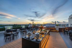 an outdoor patio with tables and chairs on a roof at Kameo Grand Hotel & Serviced Apartment, Rayong in Rayong