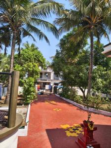 a red brick walkway with palm trees and a building at Shyams homestay MV in Malpe