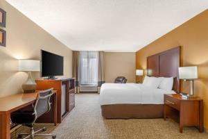 a hotel room with a bed and a desk and a tv at Comfort Inn North Conroe in Conroe