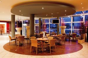 a restaurant with tables and chairs and windows at Vienna House by Wyndham Baltic Stralsund in Stralsund