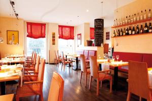 a restaurant with tables and chairs and wine bottles at Vienna House by Wyndham Baltic Stralsund in Stralsund