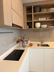 a kitchen with white cabinets and a sink and flowers at Avrora Laguna Residences Sky Park in Ban Thalat Choeng Thale