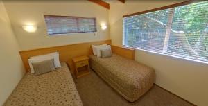 a small bedroom with two beds and a window at Creel Lodge in Turangi