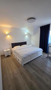 a bedroom with a white bed and a wooden floor at House in Hudum - Botoșani in Hudum