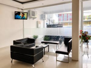 a living room with black chairs and a tv on the wall at Marina Jampea Hotel in Makassar