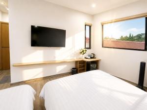 a white bedroom with a flat screen tv on the wall at The SunHill Dalat in Ấp Ða Lợi