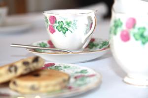 una mesa con una taza y un plato de galletas y una taza de café en Cnapan Guest House, en Newport