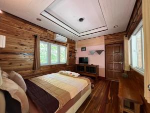 a bedroom with a bed in a room with wooden walls at Ariya Garden Home in Chumphon