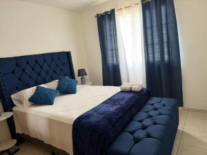 a bedroom with a large bed with blue pillows and curtains at Aloft Alvarado in Siguatepeque