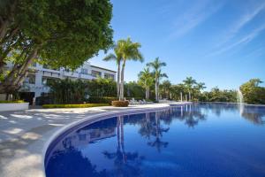 a large swimming pool with palm trees and a building at Departamento Taheima Nuevo Vallarta in Nuevo Vallarta