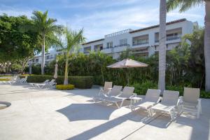 a group of chairs and an umbrella in front of a building at Departamento Taheima Nuevo Vallarta in Nuevo Vallarta