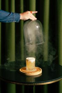 a person pointing at a glass container with a cup on a table at Ecrin Blanc Resort Courchevel - Aquapark in Courchevel +60 photos