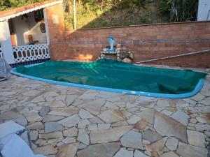 a swimming pool with a hose on a stone patio at chalé casa na mata céu Iluminado in Guararema