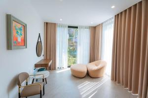 a living room with two chairs and a large window at Villa Flamingo Hải Tiến in Thanh Hóa