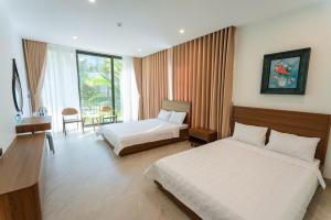 a hotel room with two beds and a desk at Villa Flamingo Hải Tiến in Thanh Hóa