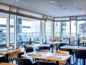 a restaurant with tables and chairs and large windows at Hilton Diagonal Mar Barcelona in Barcelona