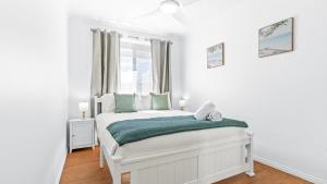 a white bedroom with a bed and a window at Keyside Escape in Forster