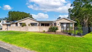a brick house with a fence in a yard at Keyside Escape in Forster