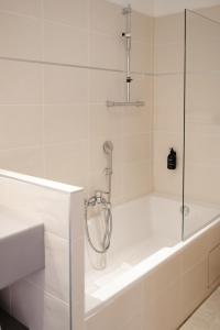 a white bathroom with a tub and a shower at Auberge du Cabestan Hotel Audierne in Audierne