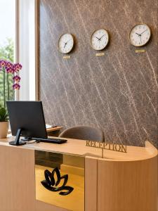 a reception desk with a laptop and clocks on the wall at Rai Premium İstanbul in Istanbul
