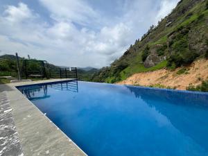 a swimming pool with blue water in front of a mountain at Stone Gale Estate Villa in Galaha Town