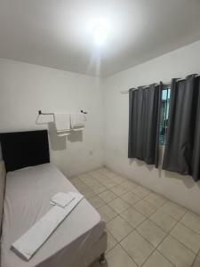 a white room with a bed and black curtains at Apartamento simples com vista para a praça in Palhoça +3 photos