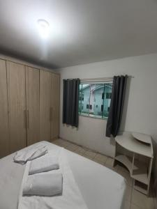 a bedroom with a bed and a desk and a window at Apartamento simples com vista para a praça in Palhoça