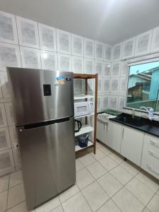 a kitchen with a stainless steel refrigerator and a sink at Apartamento simples com vista para a praça in Palhoça