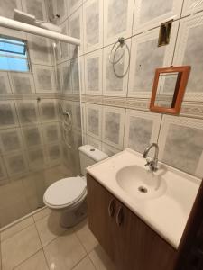 a bathroom with a toilet and a sink and a mirror at Apartamento simples com vista para a praça in Palhoça