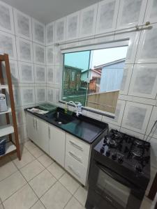 a kitchen with a sink and a stove and a window at Apartamento simples com vista para a praça in Palhoça