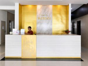 a man standing behind a counter in a lobby at Marina Jampea Hotel in Makassar