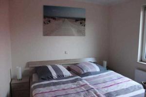 a bed in a bedroom with a picture on the wall at Ferienhaus Ostsee Antje Bellmann in Kemnitz +2 photos