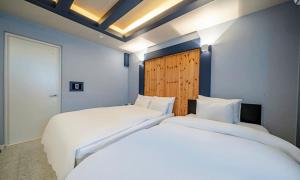 two beds in a room with white sheets at 충주 호텔 발리 in Chungju