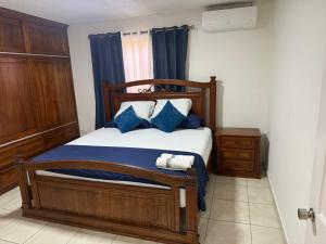 a bedroom with a wooden bed with blue pillows at Aloft Alvarado in Siguatepeque
