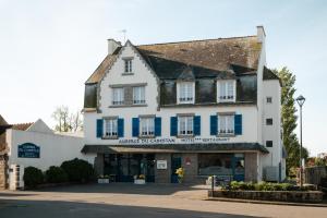 a white building with blue shutters on a street at Auberge du Cabestan Hotel Audierne in Audierne