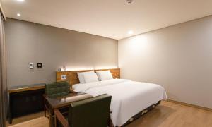 a bedroom with a large white bed and a desk at Anyang CNC Hotel in Anyang