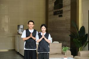 a man and a woman standing in a room with their hands in praying at Mecon Hotel in Phnom Penh