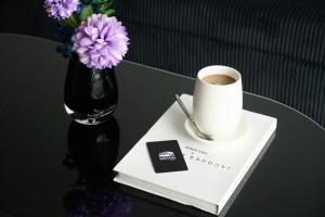 a table with a cup of coffee and a vase of purple flowers at Mecon Hotel in Phnom Penh