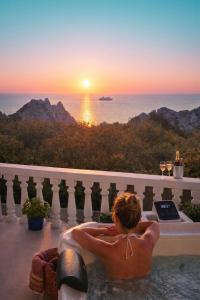 a woman sitting in a bath tub watching the sunset at Aegean Serenity - Sea View Retreat in Archangelos