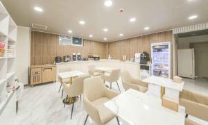 a kitchen with tables and chairs and a refrigerator at Hey, Jecheon Hotel in Chech'ŏn-yŏk