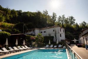 a swimming pool with chairs and a building at Agriturismo Cascina del Vai in Cairo Montenotte