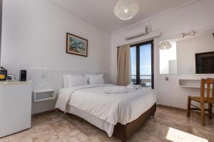 a bedroom with a large white bed with a window at Argo Rooms-Papadakis in Kissamos