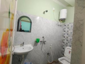 a bathroom with a sink and a toilet and a mirror at Mayur Lodge And Restaurant in Khejuria Ghāt +19 photos