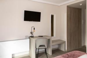 a bedroom with a desk with a chair and a tv on the wall at Hotel O'Pazo in Vigo