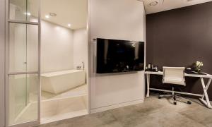 a bathroom with a tub and a tv on a wall at Hotel The May in Namyangju