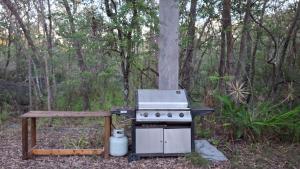 a stove and a bench next to a tree at Caravan Rustic Sunflower in Mount Crosby +10 photos