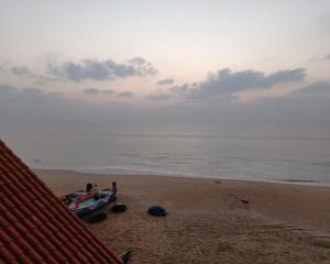 a boat sitting on a beach with the ocean at Sapphire Inn in Chennai