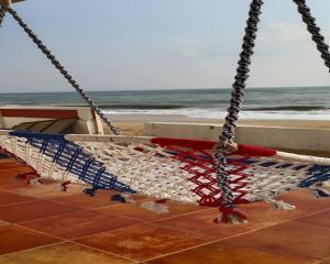 a swing on the beach with the ocean in the background at Sapphire Inn in Chennai