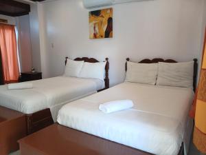 two beds in a small room with a table at JM-RN Pensione House in Padre Burgos