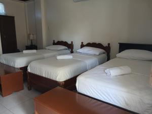 a room with four beds with white sheets at JM-RN Pensione House in Padre Burgos